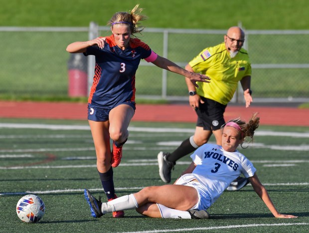 Oswego East's Anya Gulbrandsen slides under Oswego's Gillian Young to steal the ball during their Class 3A Lockport Regional semifinal game on Wednesday, May 15, 2024, in Lockport.(Jon Cunningham/for The Beacon-News)