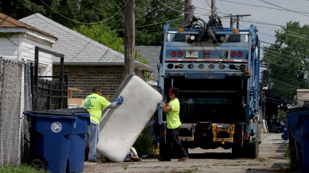 Cicero Public Works employees collect flood-damaged debris in an alley along 57th Avenue, July 6, 2023. (Antonio Perez/Chicago Tribune)