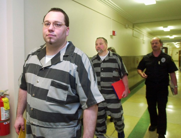 Michael Slover Jr., left, his father, Michael Slover Sr., middle, and his mother, Jeannette Slover, partially hidden, are led into a Macon County courtroom in Decatur, Illinois on June 29, 2001. The three were charged and later convicted in 2002 in the 1996 death of Slover's ex-wife, Karyn Hearn Slover. (Carlos T. Miranda/Decatur Herald & Review)