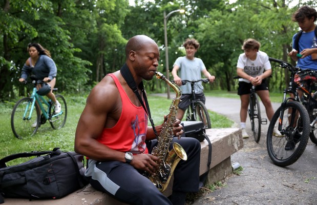 David Agori-Iwe plays the alto saxophone as a group of teenagers listen in at Clark Park in Chicago on Memorial Day on May 27, 2024.  Agori-Iwe is new to Chicago having just moved South Florida to Chicago's Roscoe Village neighborhood.  (Chris Sweda/Chicago Tribune)