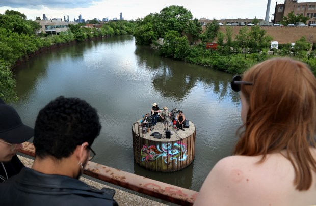 People look on from the Belmont Ave. overpass as a band performs atop a circular concrete pillar on the Chicago River during a Secret River concert on Memorial Day on May 27, 2024. (Chris Sweda/Chicago Tribune)