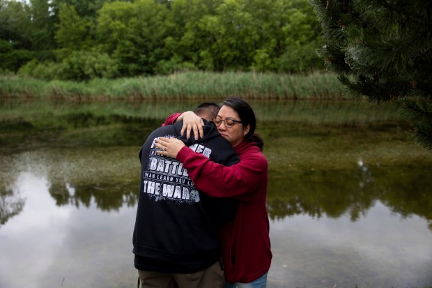 Panita Luangkesorn, right, comforts her husband, Ryan Killacky, a veteran who served in Afghanistan, after he became emotional during the annual Rosehill Memorial Day cemetery ceremony on Monday, May 27, 2024, at Rosehill Cemetery in Chicago. (Vincent Alban/Chicago Tribune)