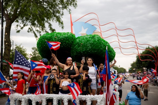 Parade participants wave to spectators during the 46th Puerto Rican People's Day Parade on on June 8, 2024, in Humboldt Park in Chicago. (Vincent Alban/Chicago Tribune)