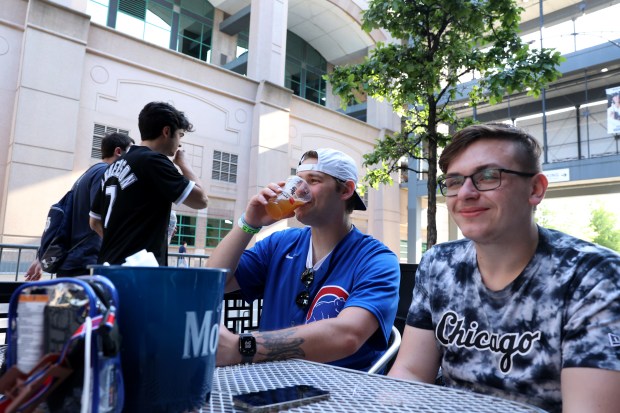 Nicholas Koff, center, drinks a beer while hanging out with Ben Havard and Brooke Coleman (not pictured) as they relax outside of Guaranteed Rate Field before a game between the Chicago White Sox and the Baltimore Orioles on May 23, 2024. The group attended the Cubs game earlier in the day at Wrigley Field before boarding the CTA Red Line train and arriving for the Sox game. (Chris Sweda/Chicago Tribune)