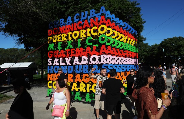 Concertgoers walk past an art piece with names of Latin American countries during the Sueños Music Festival at Grant Park on the first day on May 25, 2024, in Chicago. (John J. Kim/Chicago Tribune)