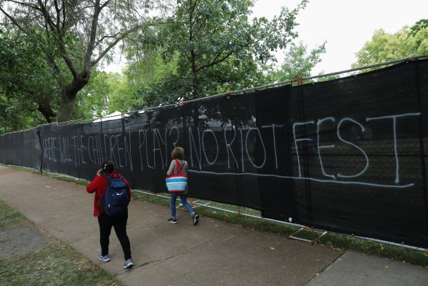 People walk by fencing following the Riot Fest music festival at Douglass Park in Chicago on Sept. 20, 2021. (José M. Osorio/ Chicago Tribune)